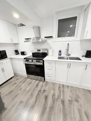 a kitchen with white cabinets and a sink and a stove at Modern & cozy one Bedroom Basement Suite with Kitchen and parking- sleeps 4 in Mississauga