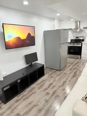 a living room with a television and a refrigerator at Modern & cozy one Bedroom Basement Suite with Kitchen and parking- sleeps 4 in Mississauga