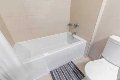 a white bathroom with a tub and a toilet at Luxury 1BR Suite w Skyline City Views - The Roland in Toronto