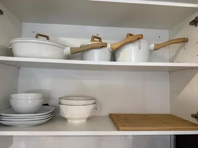 a kitchen shelf with white bowls and utensils at Bright Escape Falls Retreat in Niagara Falls