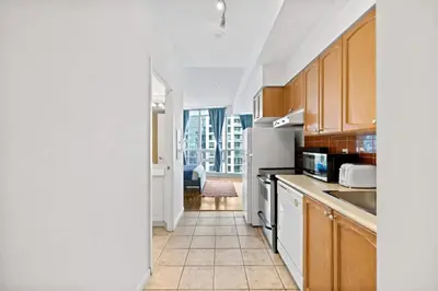 a kitchen with wooden cabinets and a white refrigerator at Chic Fort York Studio Cozy Retreat in Downtown TO in Toronto