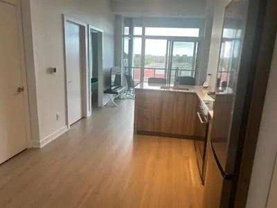 an empty living room with a wooden floor and a desk at Luxury Condo with Hottub, outdoor firepit & Bowlin in Kitchener