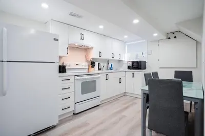 a kitchen with white cabinets and a table and a refrigerator at Stylish, Spacious 6-Bedroom Home in the GTA in Whitby