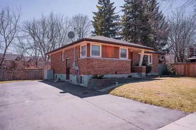 a small brick house with a driveway at Stylish, Spacious 6-Bedroom Home in the GTA in Whitby
