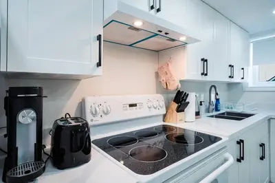 a white kitchen with a stove and a sink at Stylish, Spacious 6-Bedroom Home in the GTA in Whitby