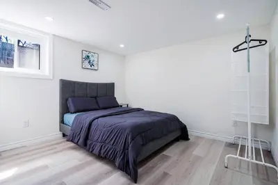 a bedroom with a bed in a white room at Bright & Cozy Home in the GTA (Basement Apartment) in Whitby