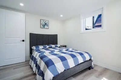 a bedroom with a bed with a blue and white comforter at Bright & Cozy Home in the GTA (Basement Apartment) in Whitby