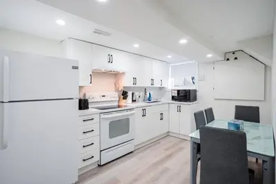 a kitchen with white cabinets and a glass table at Bright & Cozy Home in the GTA (Basement Apartment) in Whitby