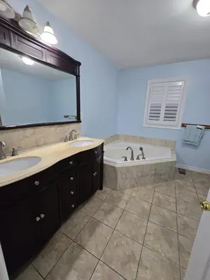a bathroom with two sinks and a tub with a mirror at Peaceful Country Home on 25 Acres of Wooded Land in Alliston