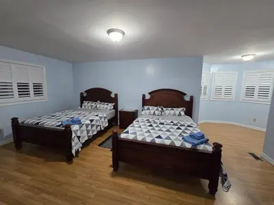 two beds in a bedroom with blue walls and wooden floors at Peaceful Country Home on 25 Acres of Wooded Land in Alliston