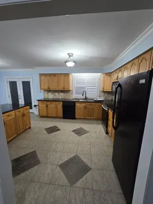 a kitchen with wooden cabinets and a black refrigerator at Peaceful Country Home on 25 Acres of Wooded Land in Alliston