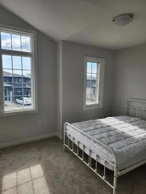 a bedroom with a bed and two windows at Sunrise Villa in Fort Erie