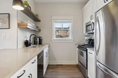 a kitchen with white cabinets and a stainless steel refrigerator at Alpine Breeze Getaway at Blue in Blue Mountains