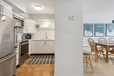 a kitchen with white cabinets and a table with chairs at Slopeside Ski In Ski Out Second Floor Condo in Blue Mountains