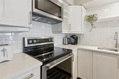 a kitchen with white cabinets and a stove top oven at Slopeside Ski In Ski Out Second Floor Condo in Blue Mountains