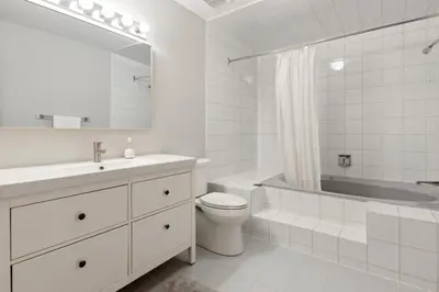 a white bathroom with a sink and a tub and a toilet at Slopeside Ski In Ski Out Second Floor Condo in Blue Mountains