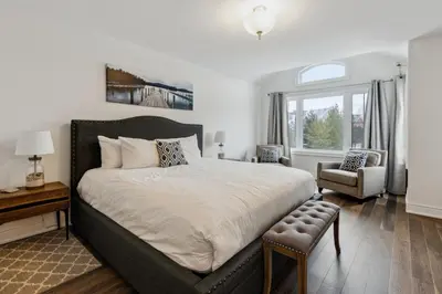 a bedroom with a large bed and a chair at Family Townhome in Historic Snowbridge in Blue Mountains
