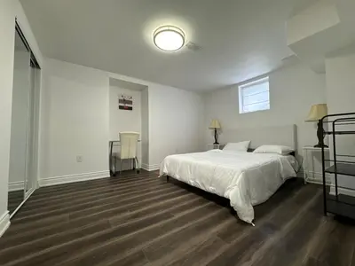 a bedroom with a white bed and a wooden floor at Basement Suite 2 bedroom s in Oshawa