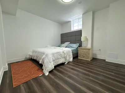 a bedroom with a bed and a night stand and a window at Basement Suite 2 bedroom s in Oshawa