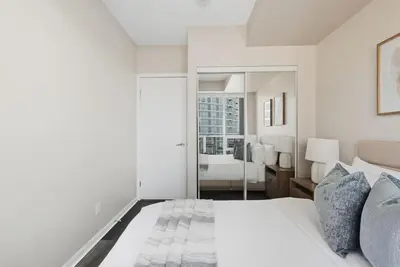 a bedroom with a white bed and a large mirror at Modern Lakeside 1BR Condo in Downtown Toronto in Toronto