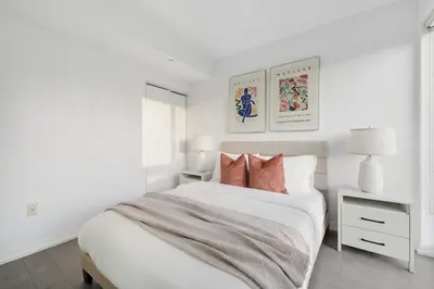 a white bedroom with a white bed with pink pillows at Bright 2BR Condo w Patio Central Toronto Retreat in Toronto