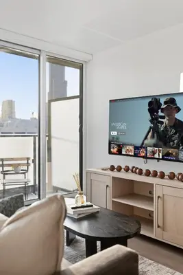 a living room with a tv and a couch and a table at Bright 2BR Condo w Patio Central Toronto Retreat in Toronto