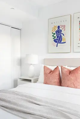 a white bedroom with a white bed with pink pillows at Bright 2BR Condo w Patio Central Toronto Retreat in Toronto