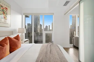 a bedroom with a white bed with a large window at Bright 2BR Condo w Patio Central Toronto Retreat in Toronto