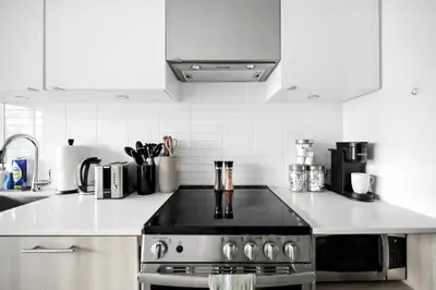a kitchen with a stainless steel stove and white cabinets at Luxe Downtown Studio Near Eaton Centre & Transit in Toronto