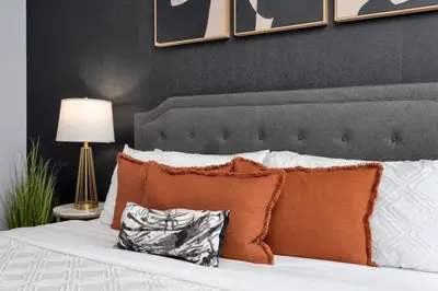 a bed with orange pillows and a black wall at Glamorous City Escape King Bed & CN Tower Views in Toronto