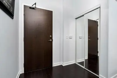 a hallway with a wooden door and a mirror at Glamorous City Escape King Bed & CN Tower Views in Toronto