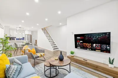 a living room with a couch and a tv on a wall at Stylish 3BR Urban Retreat near Christie Sleeps 6 in Toronto