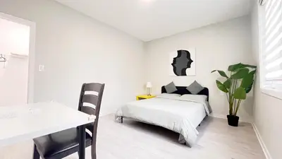 a white bedroom with a bed and a desk at Yonge Finch Subway Modern Suite with En Suite Bathroom in Toronto