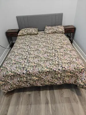 a bed with a flowered bedspread and two pillows at Pleasant stay Mississauga in Mississauga