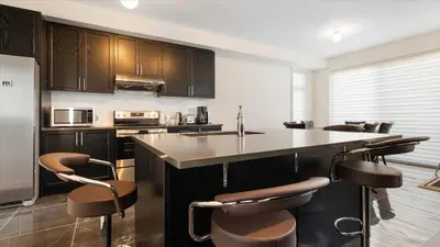 a kitchen with brown cabinets and a island with bar stools at Modern Bay Vista Getaways in Carrying Place