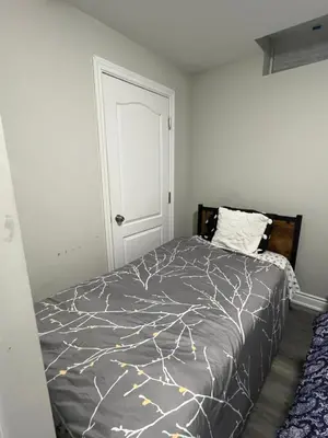 a bedroom with a bed with a gray comforter at Basement in Brampton