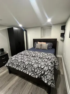 a bedroom with a bed with a black and white comforter at Basement in Brampton