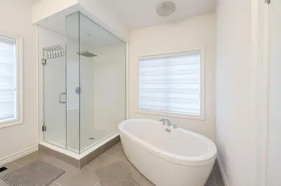 a white bathroom with a tub and a glass shower at Lux 3 Bedroom Home near Public Transit in Brampton