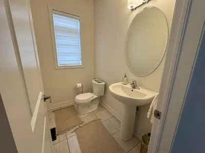 a bathroom with a sink and a toilet and a mirror at Lux 3 Bedroom Home near Public Transit in Brampton