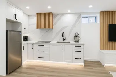 a kitchen with white cabinets and a stainless steel refrigerator at Lux Basement Apartment Getaway in Brampton