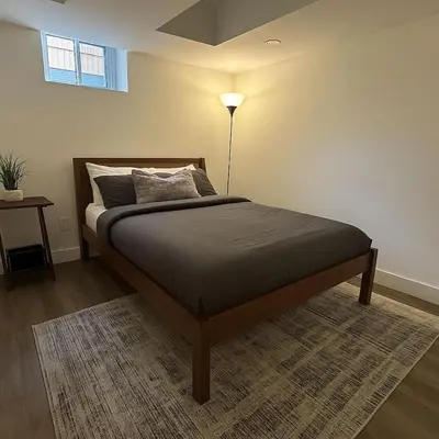 a bedroom with a bed with a lamp on a rug at Lux Basement Apartment Getaway in Brampton