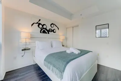 a white bedroom with a large white bed and two lamps at Downtown Luxury Unit in Toronto