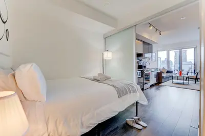 a white bedroom with a bed and a living room at Downtown Luxury Unit in Toronto