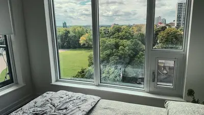 a bedroom with large windows and a bed in front thereof at LuxCondo in the Downtown Kitchener Uptown Waterloo in Kitchener