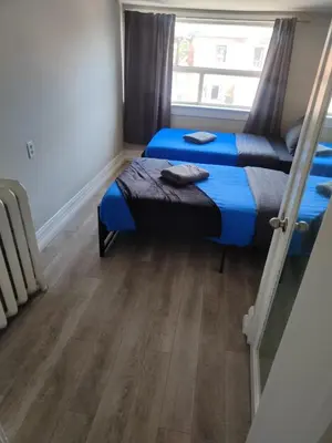 a room with two beds and a window at THE BLOOR AC SUITE-Free Wifi-Train-Bus Stop Next Door in Toronto