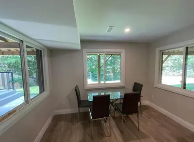 a dining room with a table and chairs and windows at Luxurious Pvt room & Pvt heated floor bathroom near Airport in Kitchener