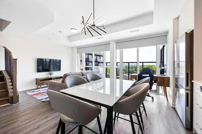 a dining room and living room with a table and chairs at Skyline Escape • 3BR Penthouse with Terrace in Toronto