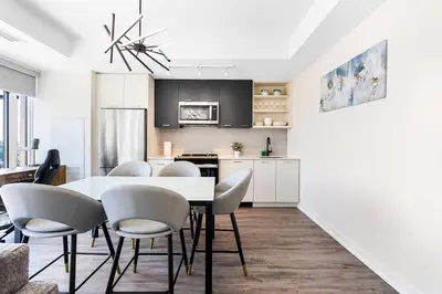 a kitchen and dining room with a white table and chairs at Skyline Escape • 3BR Penthouse with Terrace in Toronto