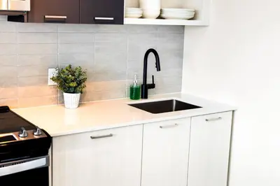 a kitchen with white cabinets and a sink at Skyline Escape • 3BR Penthouse with Terrace in Toronto