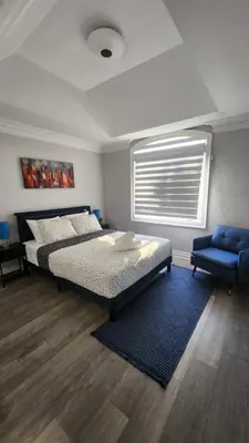 a bedroom with a bed and a blue chair at Toronto Guest House in Toronto